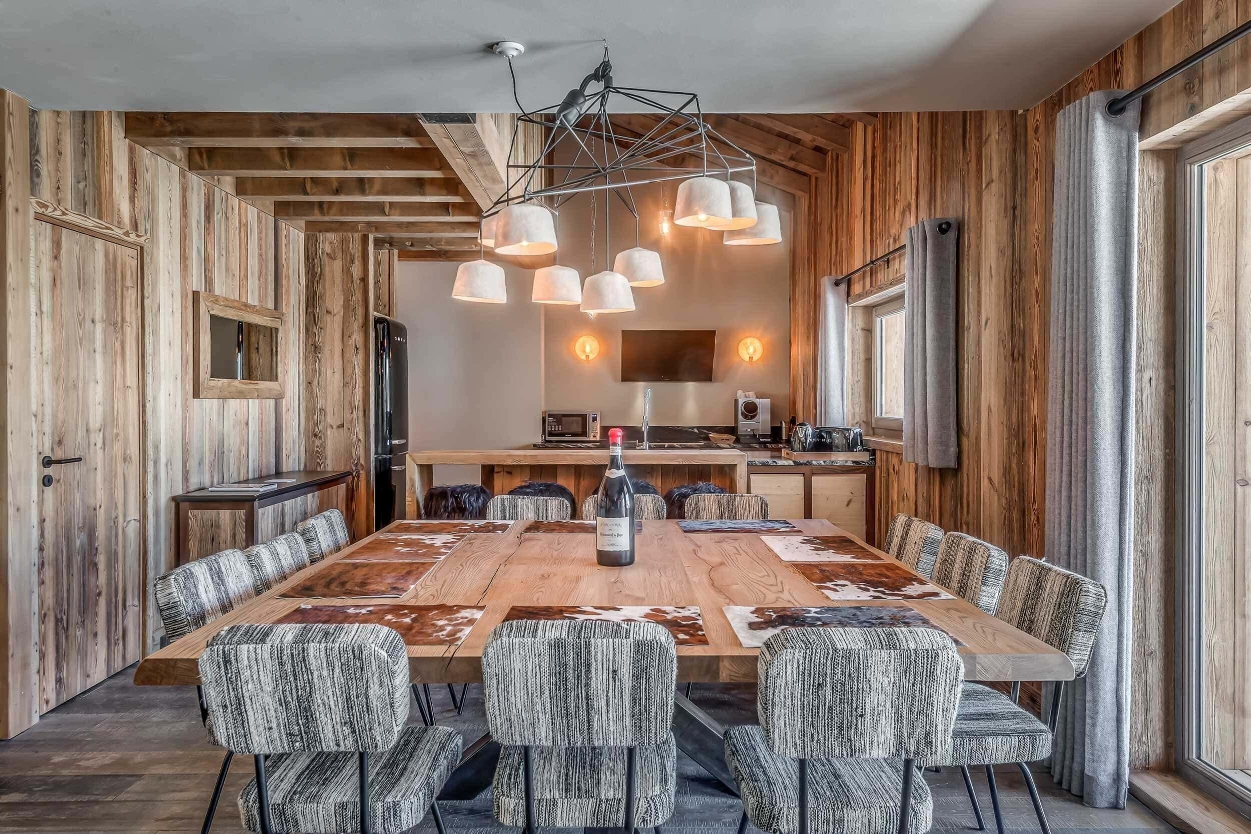 Ein Essbereich mit einem langen Holztisch, gemusterten Stühlen und Pendelleuchten.