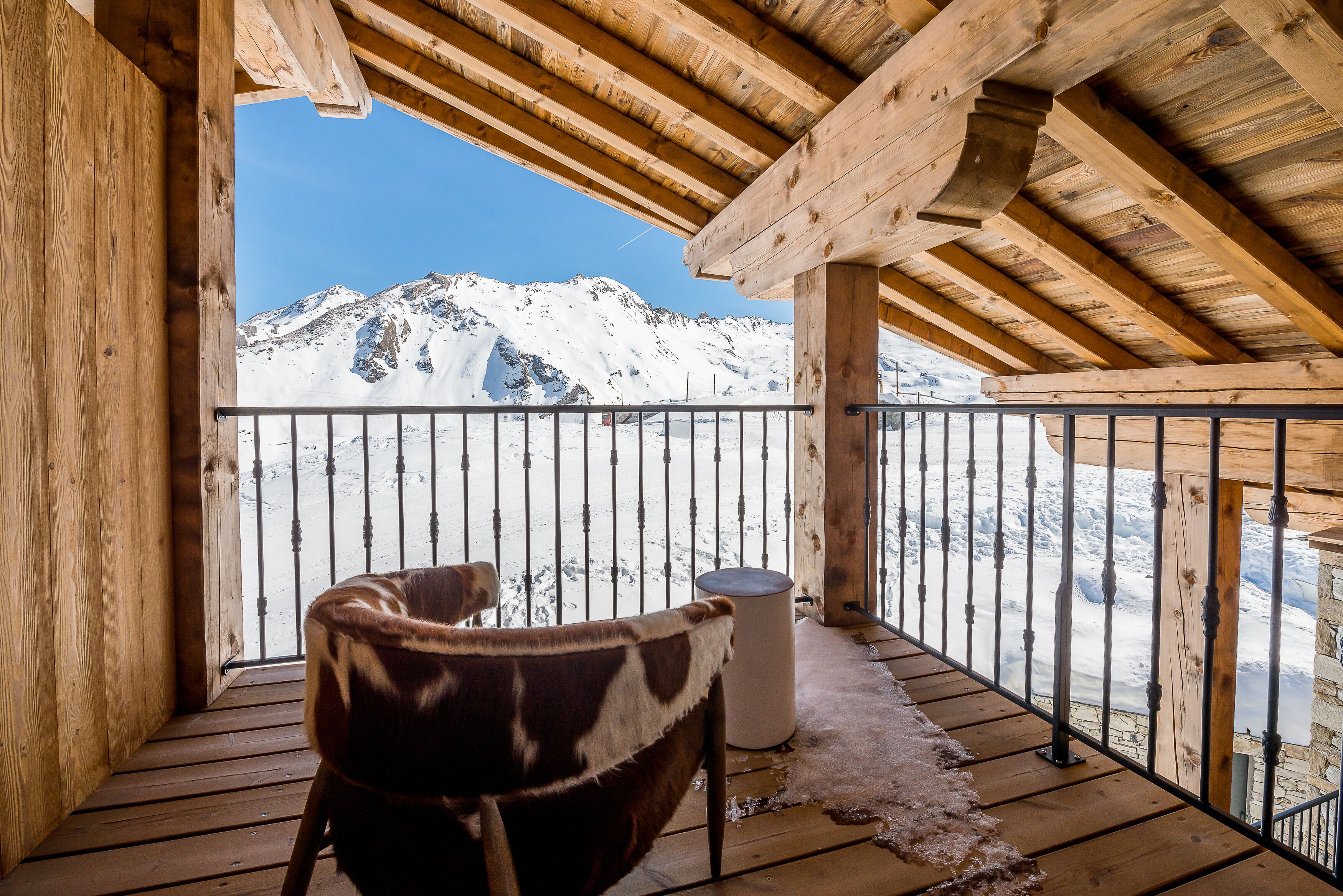 Un balcon en bois offrant une vue sur des montagnes enneigées.