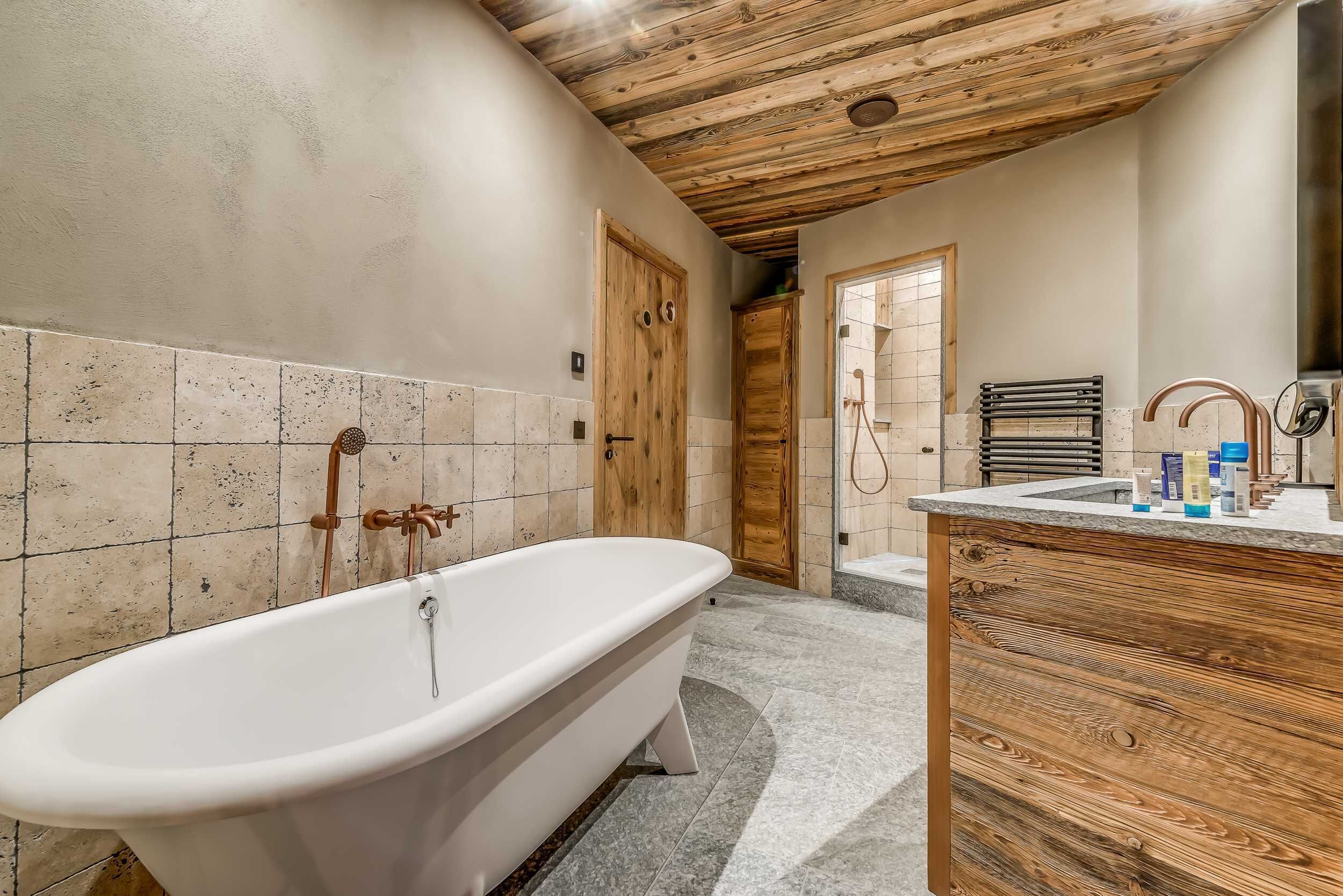 Un baño con bañera independiente, tocador de madera y zona de ducha.