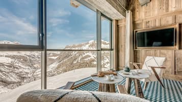 Enjoy a peaceful retreat with a breathtaking mountain view from the comfort of this cozy room, featuring a comfortable armchair and a flat-screen TV.