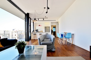 Enjoy the city view from this spacious living area with a glass coffee table, comfortable seating, and a dining space.
