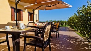 An outdoor dining area with tables and chairs, umbrellas, and a view of the sea. - Olistella (Palazzolo dello Stella)
