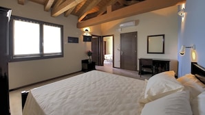 A bedroom with a large bed, wooden ceiling beams, a desk, and a chair. - Olistella (Palazzolo dello Stella)