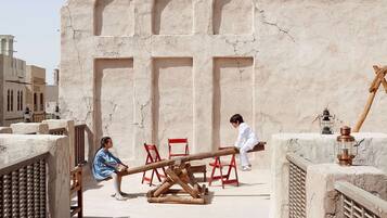 A courtyard with a seesaw, a wooden bench, and a red chair.