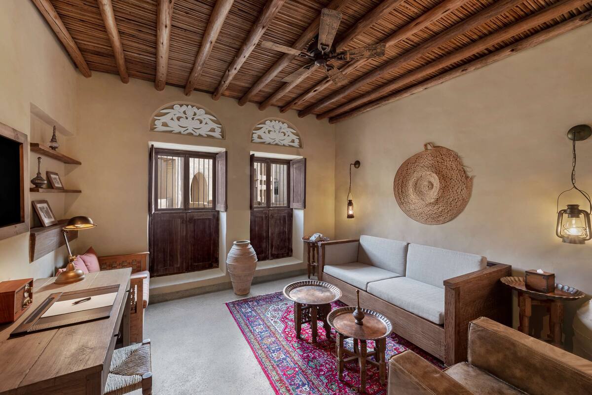 Une pièce chaleureuse avec un plafond en bois, un canapé, une table avec une lampe et un grand vase.