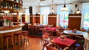 A cozy restaurant with wooden furniture, a bar area with bottles, and large windows allowing natural light. - Hotel Villa Fröhlich (Ostseebad Baabe)