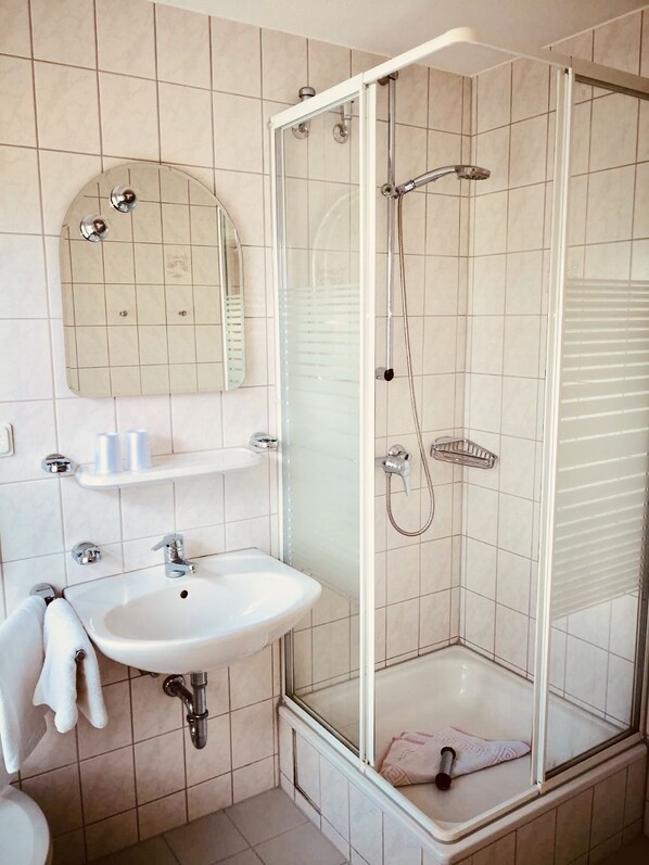 Un baño moderno con ducha de vidrio, lavamanos y espejo.