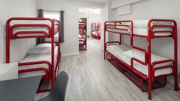 A dormitory room with bunk beds, a desk, and a chair.