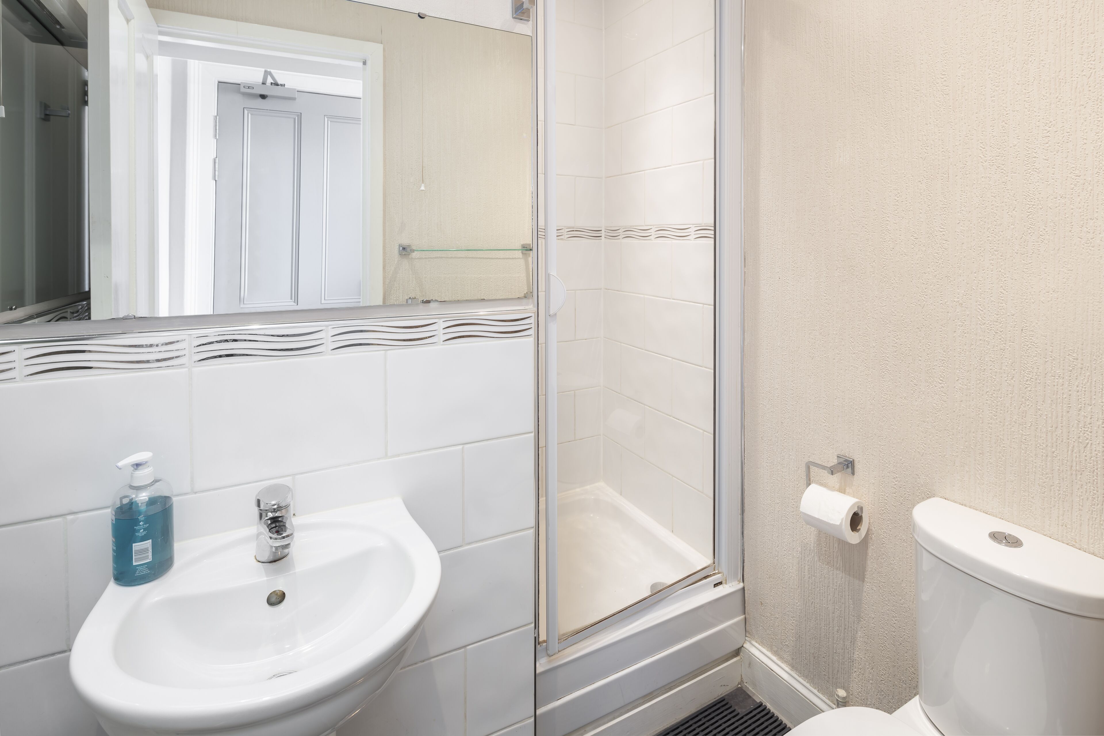 A bathroom with a white sink, a glass shower enclosure, and a toilet.