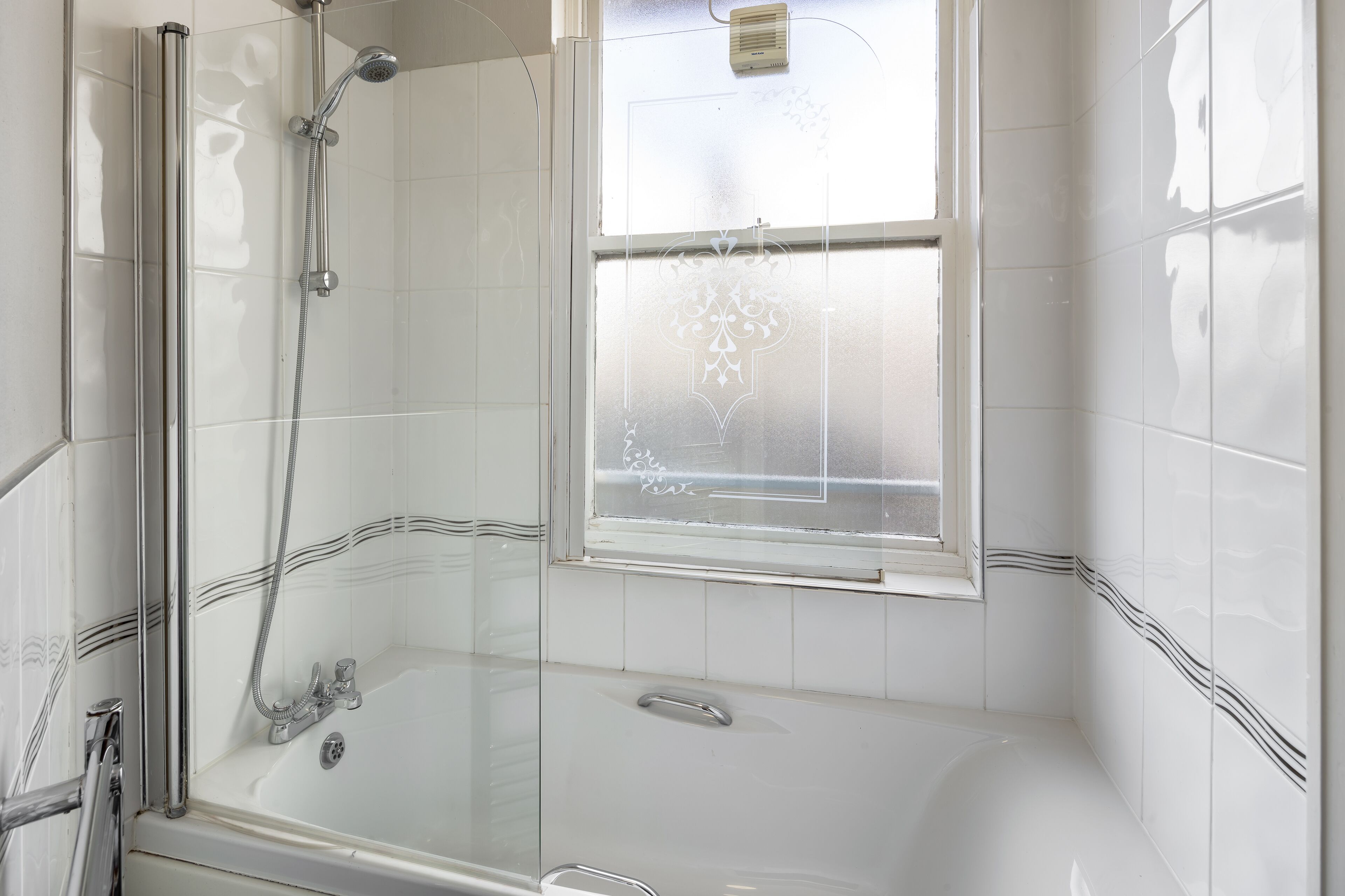 A bathroom with a glass-enclosed shower, a bathtub, and a frosted window.