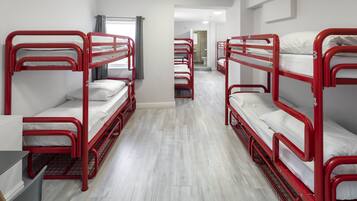 Une chambre de dortoir avec des lits superposés, un bureau et une fenêtre avec des rideaux.
