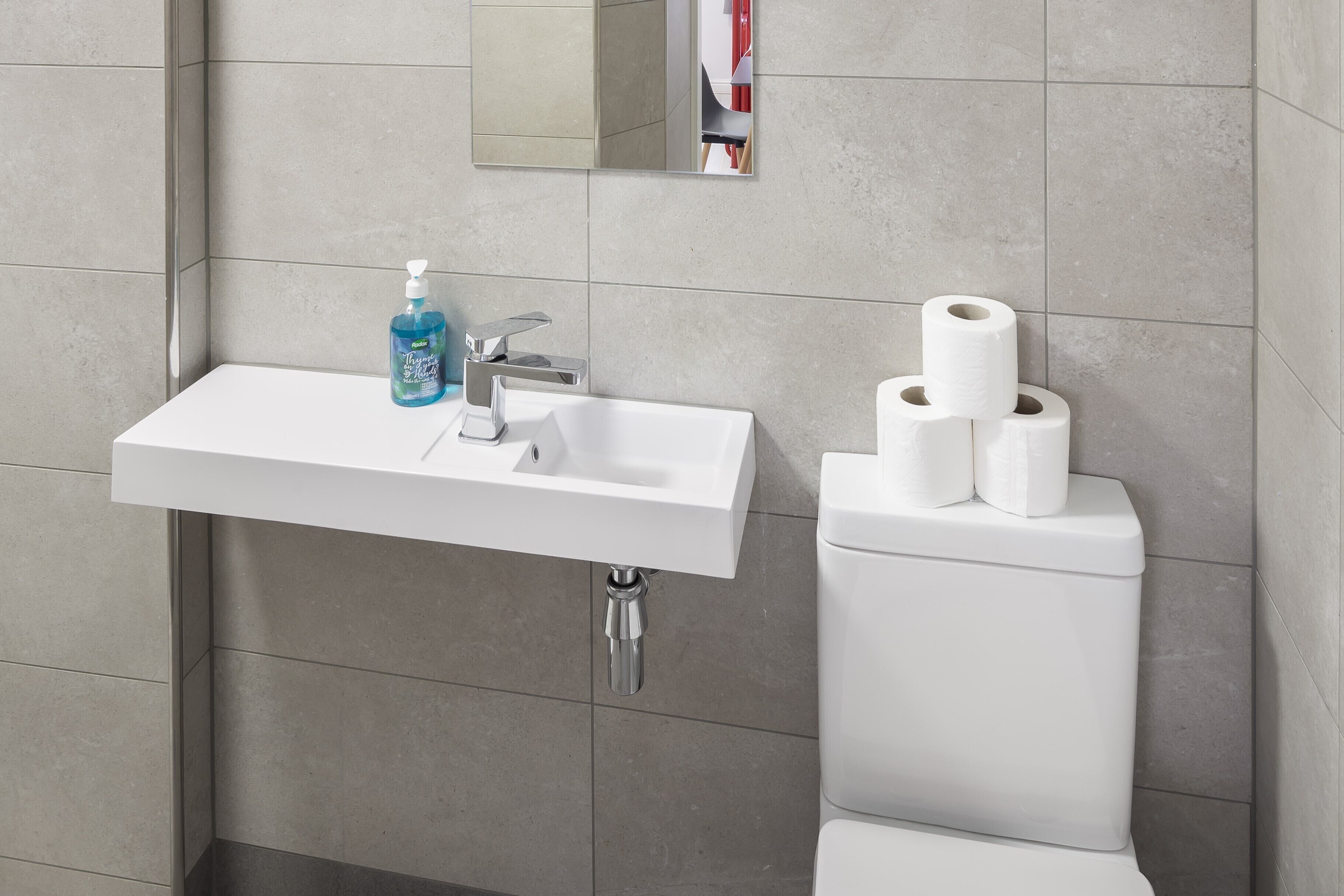 A bathroom with a white sink, a mirror, and a toilet.