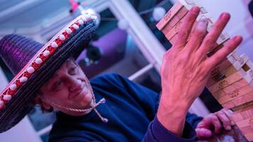 A person wearing a sombrero, holding a wooden object with text on it.