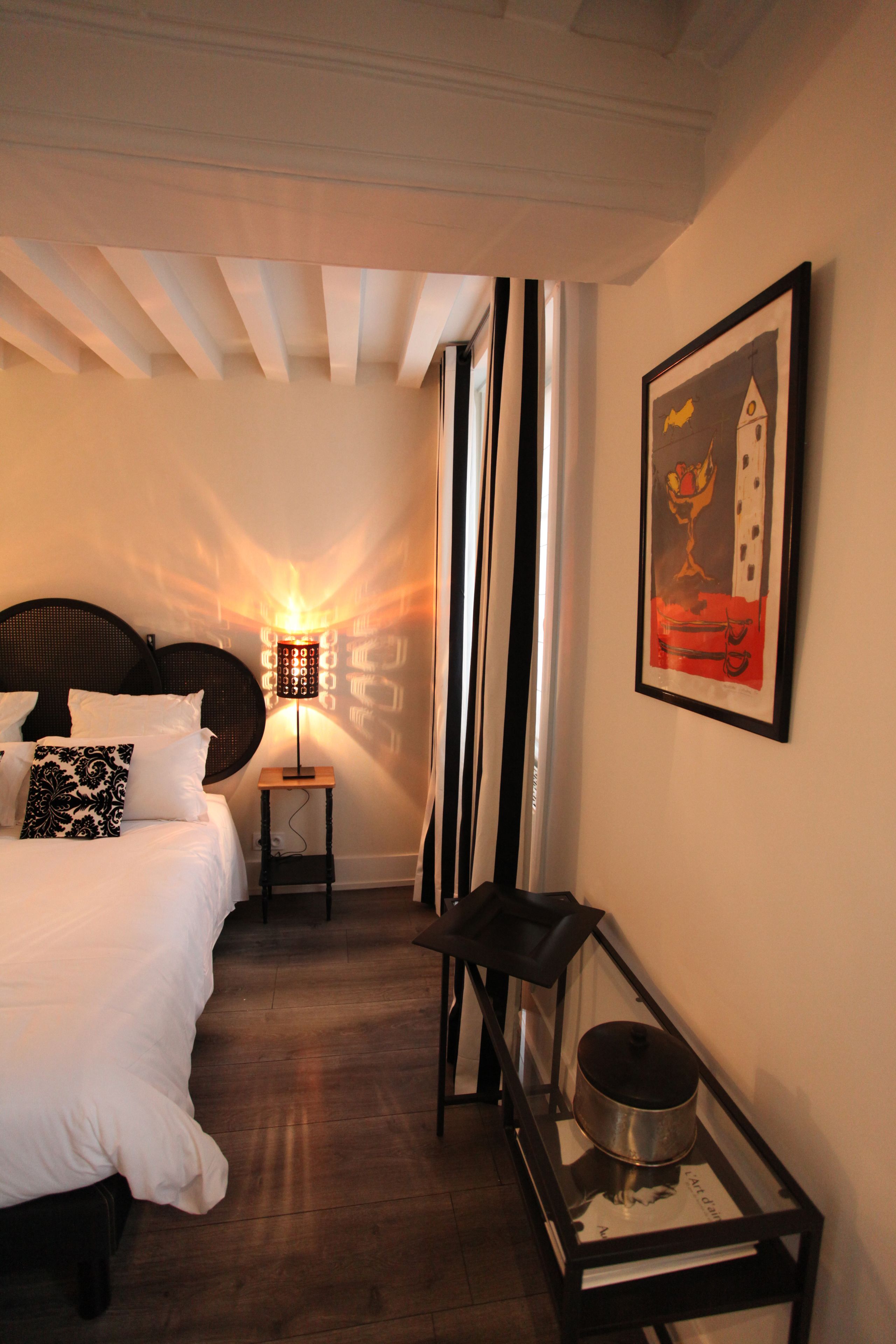 A bedroom with a bed, a nightstand, a lamp, and a framed picture on the wall.