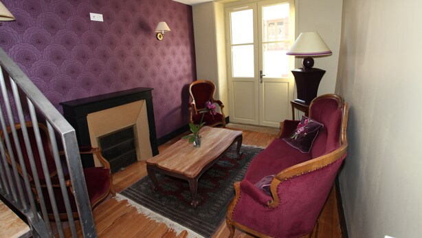 Una sala de estar con chimenea, una mesa de centro de madera, un sillón rojo y una lámpara.