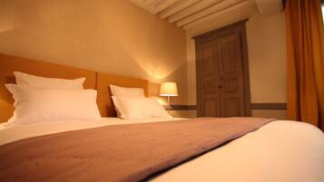 Una habitación de hotel con una cama grande, cabecera de madera, una mesita de noche con lámpara y un armario de madera.