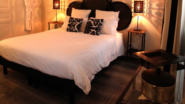 A neatly made bed with white linens, a dark wooden headboard, and two bedside lamps with patterned shades. - La Berjotine (Charolles)