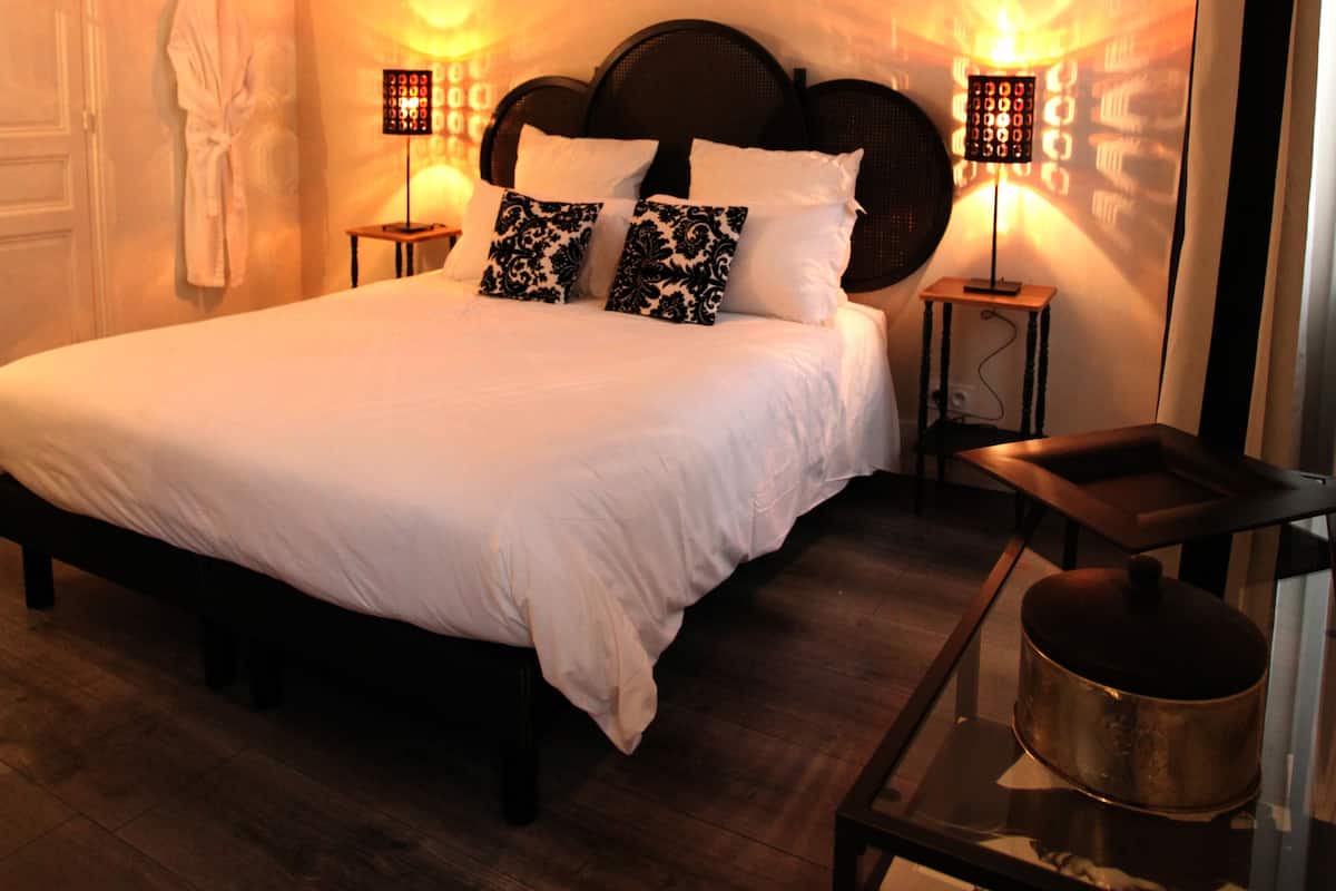 A neatly made bed with white linens, a dark wooden headboard, and two bedside lamps with patterned shades.