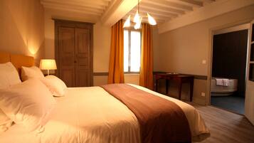 Habitación de hotel con una cama grande, un escritorio y un baño visible a través de una puerta abierta.
