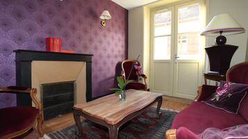 Una sala de estar con chimenea, un sofá, una mesa de centro y una lámpara.