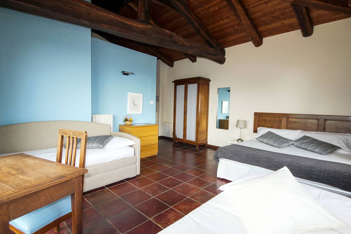 A room with a bed, a wooden table, a dresser, and a mirror.