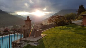 A pool with a stone structure, a grassy area, and a mountain backdrop. - Cascina del Forte (Torre Pellice)