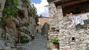 Una calle empedrada estrecha flanqueada por edificios, con balcones adornados con plantas y ropa tendida.