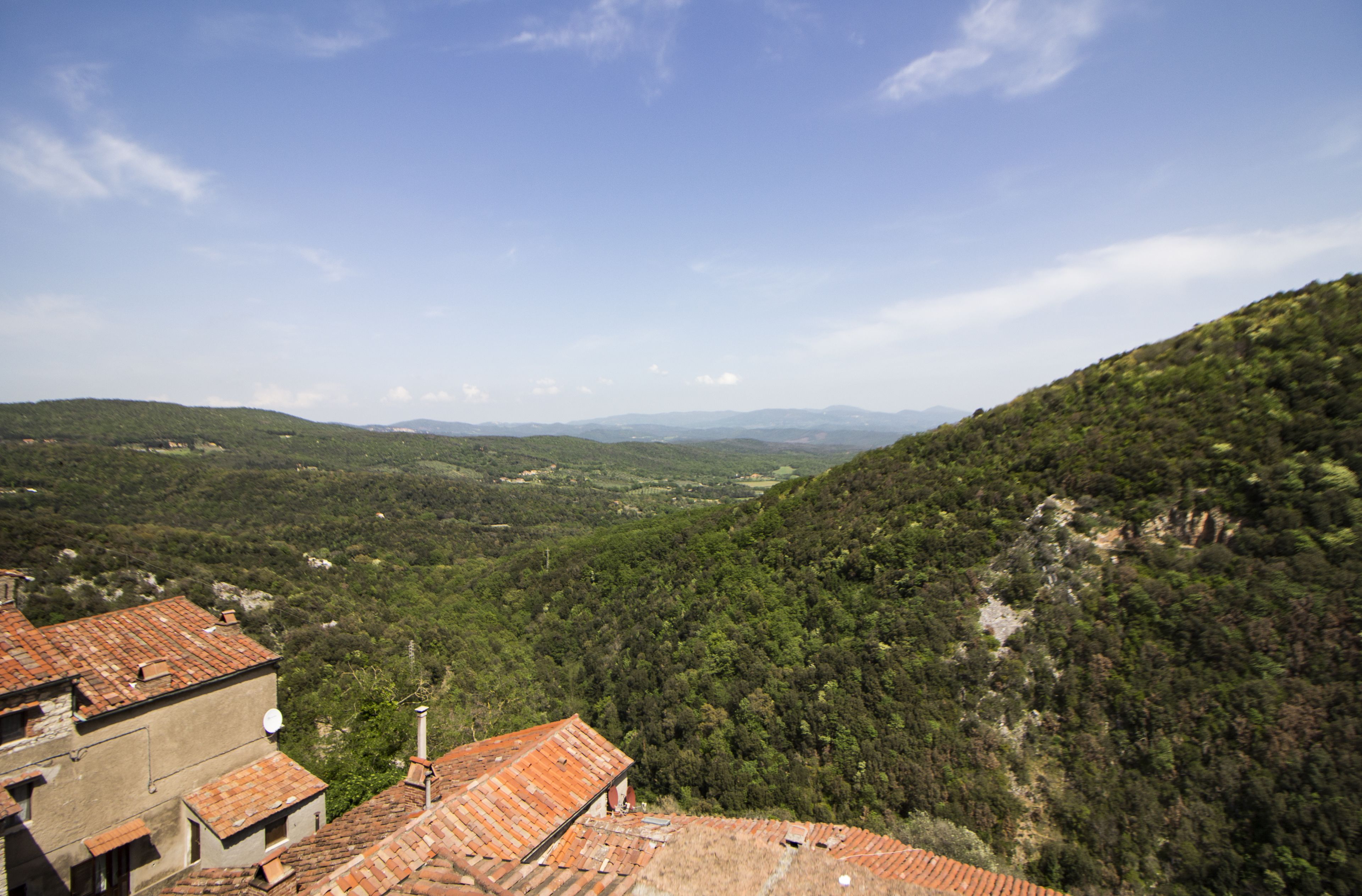 Eine gebirgige Landschaft mit terrassenförmig angelegten Feldern und traditionellen Gebäuden mit roten Ziegeldächern.