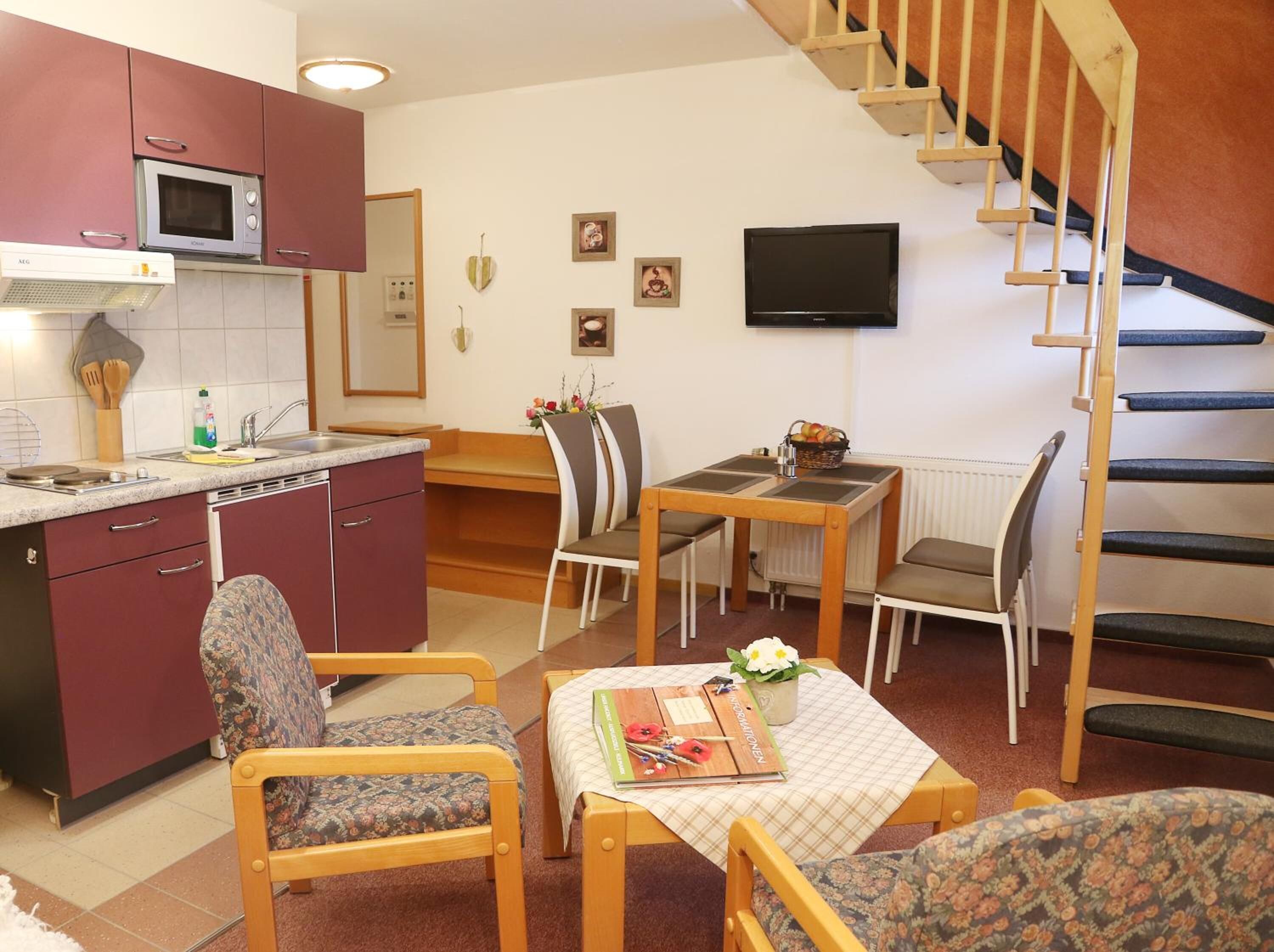 A compact living space with a kitchen, dining area, and a staircase.