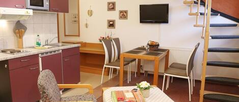 A compact living space with a kitchen, dining area, and a staircase.