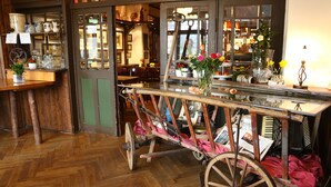 Een antieke kar met bloemen en een glazen vaas in een knus interieur met houten details en een visgraatvloer.