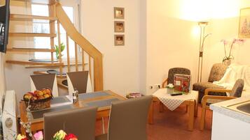 A cozy living room with a dining area, a staircase, and a kitchen.
