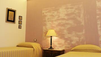 A hotel room with two single beds, a nightstand with a lamp, and a wall with a textured mural.