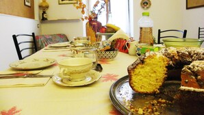 A dining table with various dishes, a loaf of bread, and a vase with flowers. - B&B Al Ponte Vecchio (Perugia)