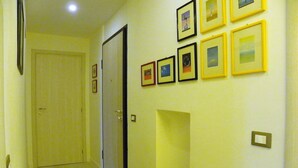 A hallway with a door, framed pictures on the wall, and a patterned rug. - B&B Al Ponte Vecchio (Perugia)