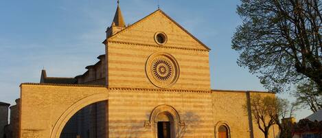 A historic church with a large arched entrance, a central circular window, and a bell tower.