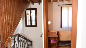 Un escalier en bois mène à une chambre à coucher qui contient un lit, une fenêtre et une petite table.