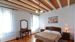 Une chambre à coucher avec un lit en bois, un bureau, une chaise, un miroir et deux lampes de chevet.