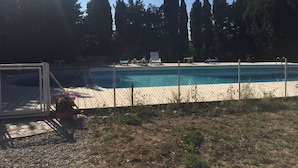 Una piscina con un borde de arena, rodeada por una cerca de alambre.
