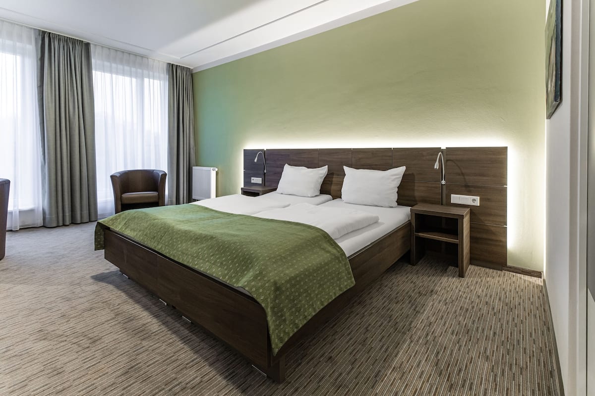 A hotel room with a large bed, a chair, a nightstand, and a lamp.