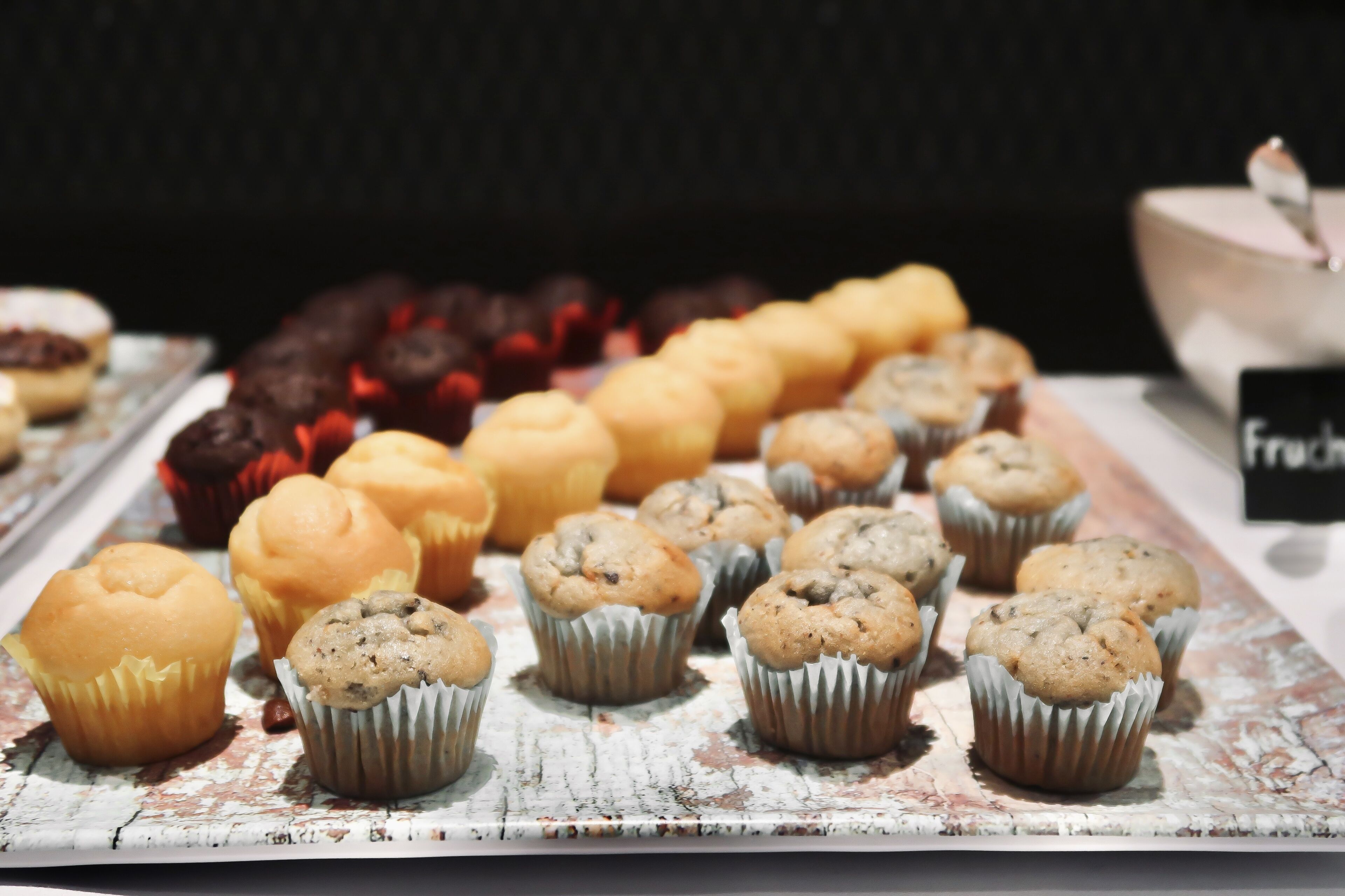 A display of various muffins and pastries on a rustic wooden table.