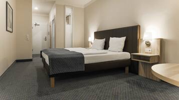 A hotel room with a bed, bedside table, and a bathroom area.