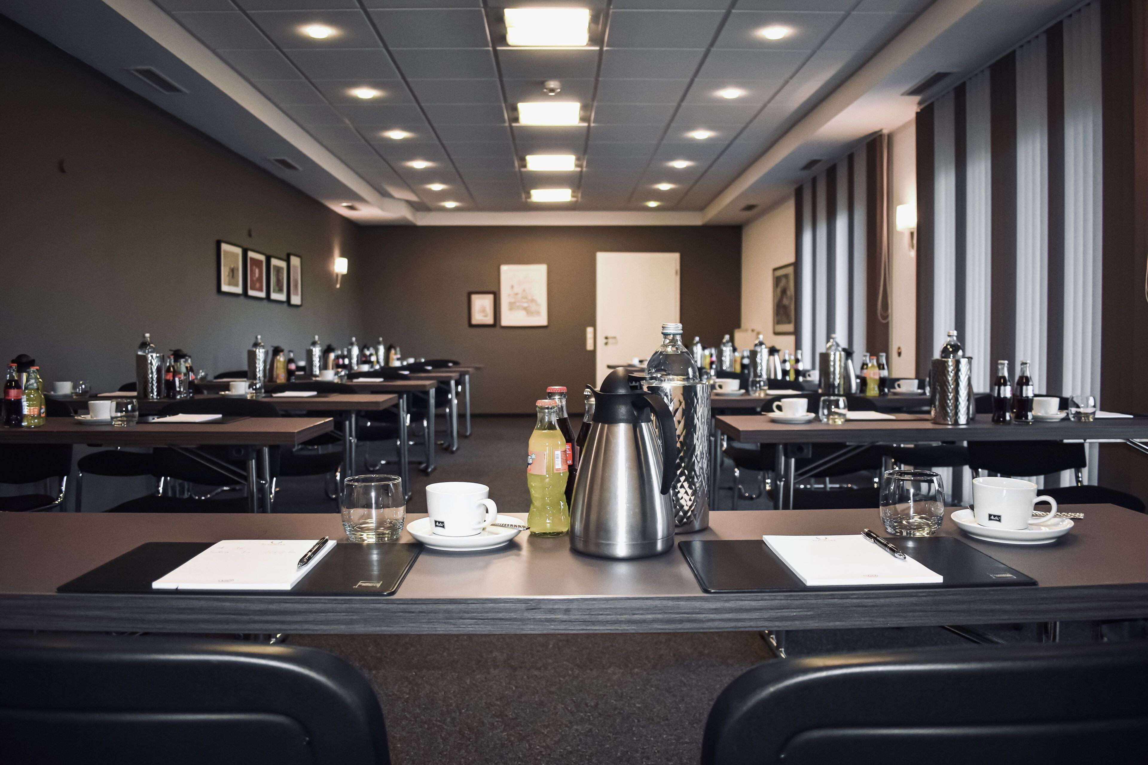 A conference room with tables, chairs, and various amenities like coffee makers, water bottles, and cups.