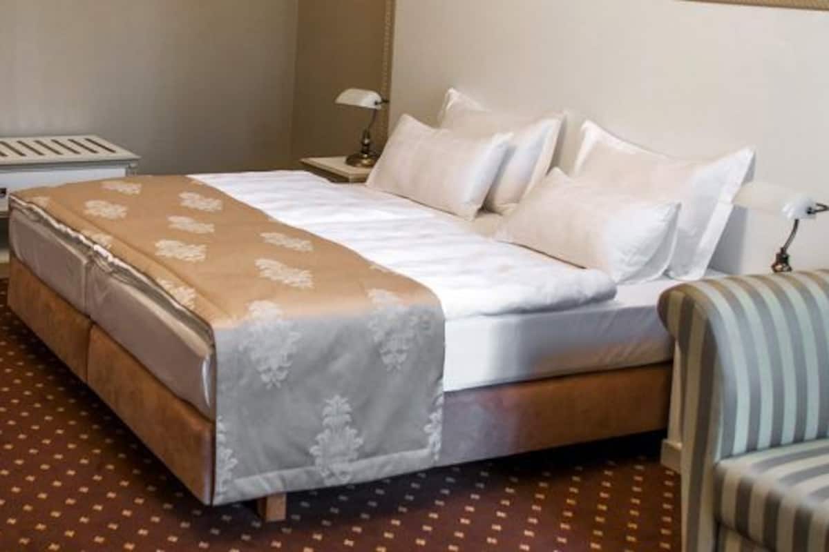 Une chambre d’hôtel avec un lit, un bureau, une chaise et un fauteuil à rayures.
