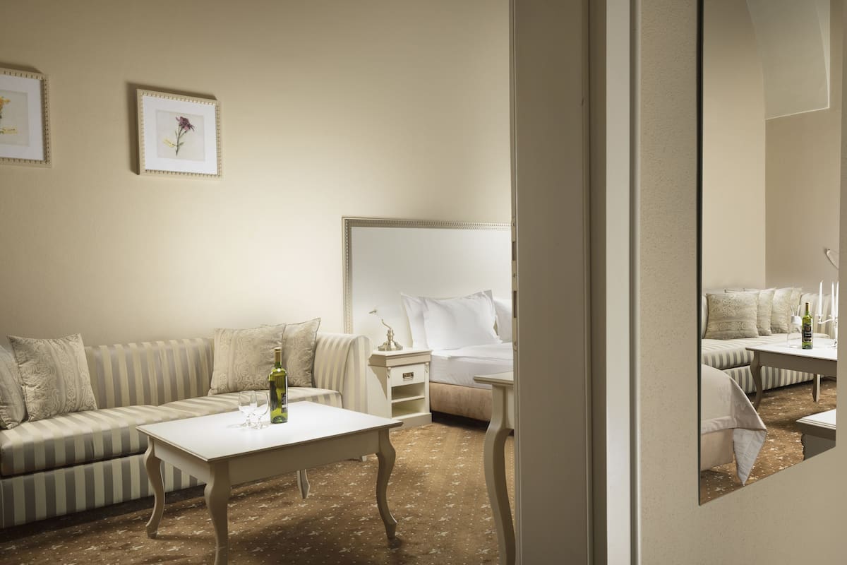 Une chambre à coucher comprenant un lit, une table de chevet, une commode, un canapé et un miroir.