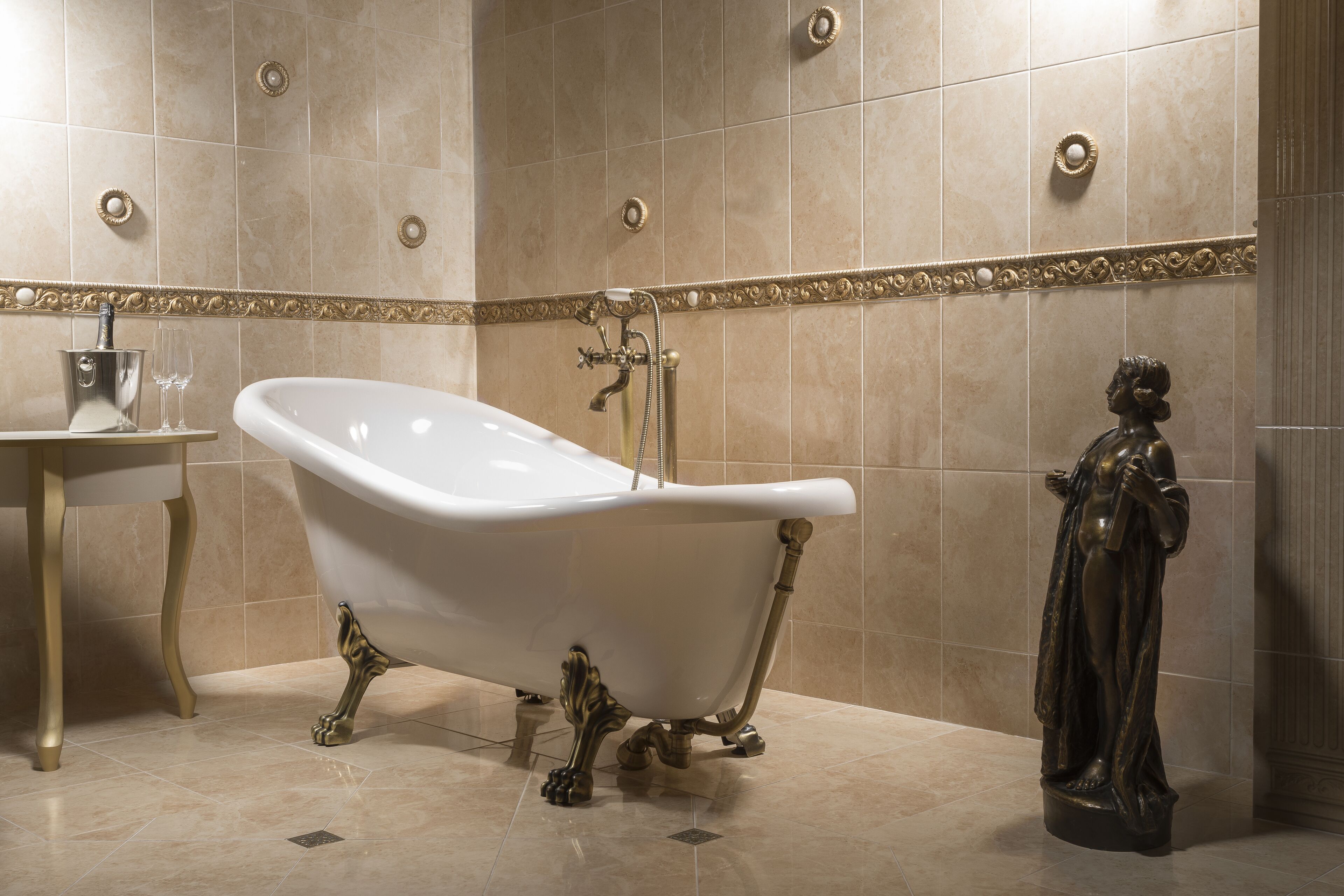 Un baño con una bañera independiente, un lavamanos pedestal y una estatua.