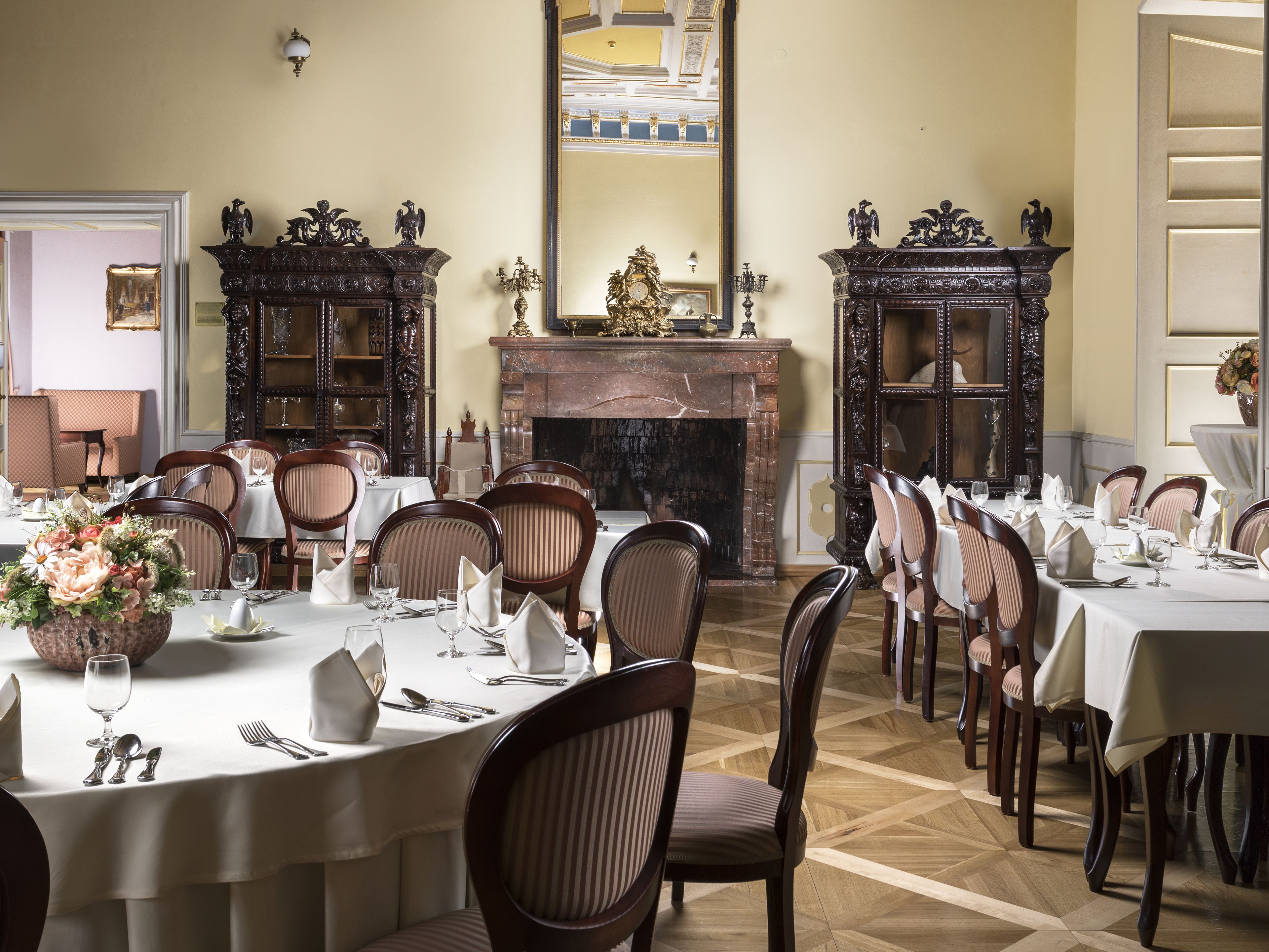 Une salle à manger élégante, avec des tables rondes, des chaises et une cheminée.