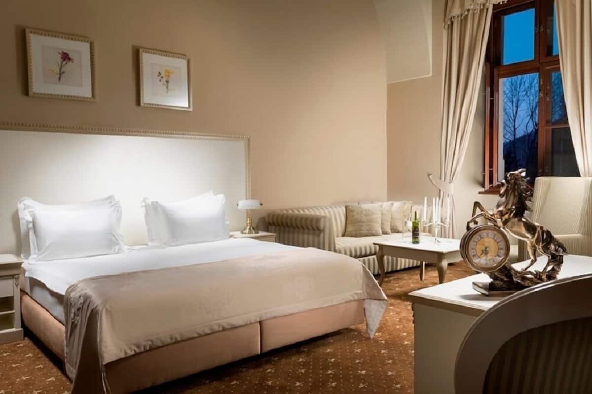Une chambre d’hôtel avec un grand lit, un canapé, une table basse et une horloge décorative.