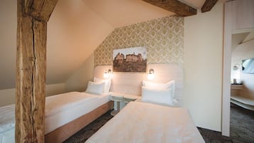 Ein Hotelzimmer mit zwei Einzelbetten, einem Holzbalken an der Decke, einem gemusterten Wandpapier und einem gerahmten Bild an der Wand.