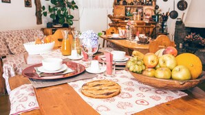Ein Esstisch ist reichhaltig mit Früchten, Kuchen und einem Saftkrug gedeckt.